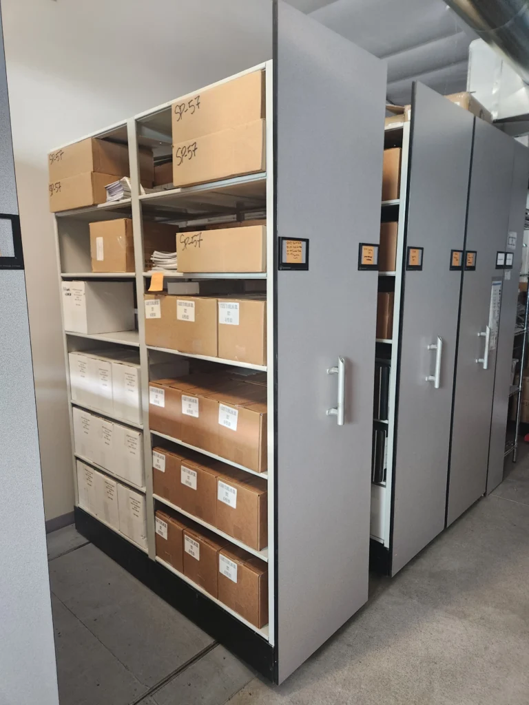 White and brown cardboard boxes stacked on rolling shelves.