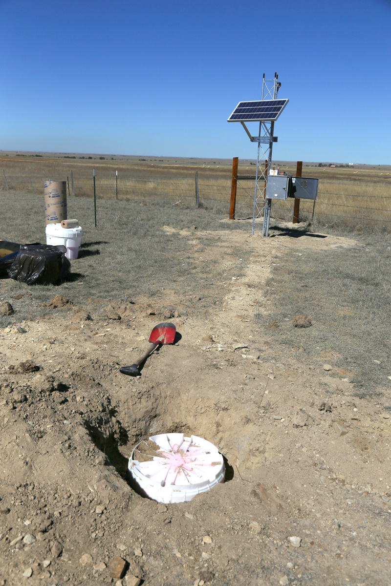 Seismometer housing in foreground with complete PV power and data transmission tower in background, Briggsdale, Colorado, May 2016. Photo credit: Mike Bornowski for the CGS.