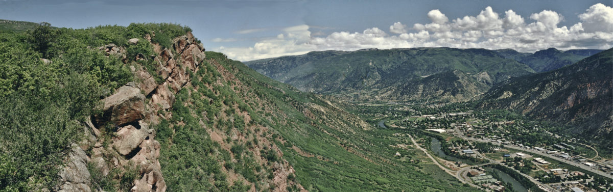 Figure 1 -- Valley rim west of the Roaring Fork River in Glenwood Springs looking north towards the confluence with the Colorado River. Note slumped (tilted) Maroon Formation sandstone blocks in the exposed rock layer. Some of the rock blocks shown in this picture from 1994 have now fallen/rolled to the valley floor. Photo credit: Jon White for the CGS.