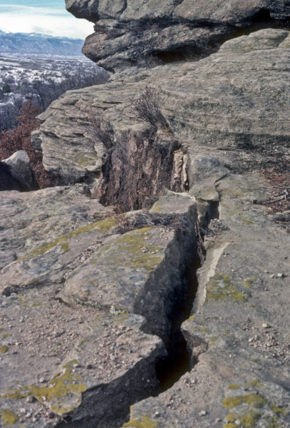 Fresh fracture line, note in the center exposed vegetation roots that were previously wedged between the fallen block and the rest of the Castle Rock Conglomerate cliff, Castle Rock, Colorado, January 1981. Photo credit: Colorado Geological Survey.