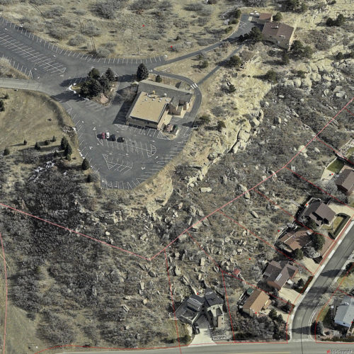Fractures in the cliff and large fallen blocks on the slope above these homes indicate an active rockfall zone, red lines reflect property boundaries. St. Francis of Assisi Church, Castle Rock, Colorado, January 1981. Photo credit: Douglas County Planning Department.