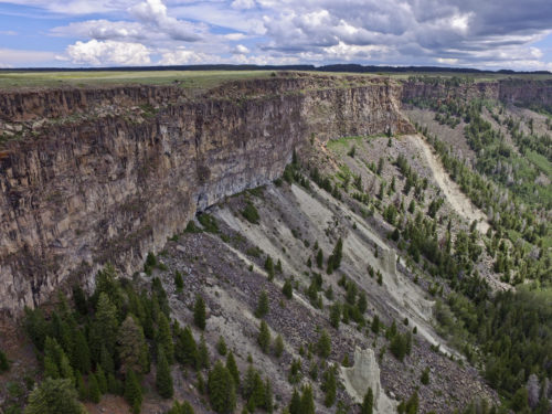 A drone shot of the layered Miocene basalts of the Grand Mesa Volcanic Field. The tan Green River Formation (Paleogene)—forming the hoodoos—is seen beneath talus accumulations at the base of the basalt flows, Lands End, Grand Mesa, Colorado, July 2017. Photo credit: Julian Chesnutt for the CGS.