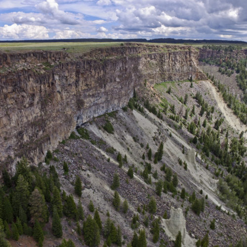 A drone shot of the layered Miocene basalts of the Grand Mesa Volcanic Field. The tan Green River Formation (Paleogene)—forming the hoodoos—is seen beneath talus accumulations at the base of the basalt flows, Lands End, Grand Mesa, Colorado, July 2017. Photo credit: Julian Chesnutt for the CGS.