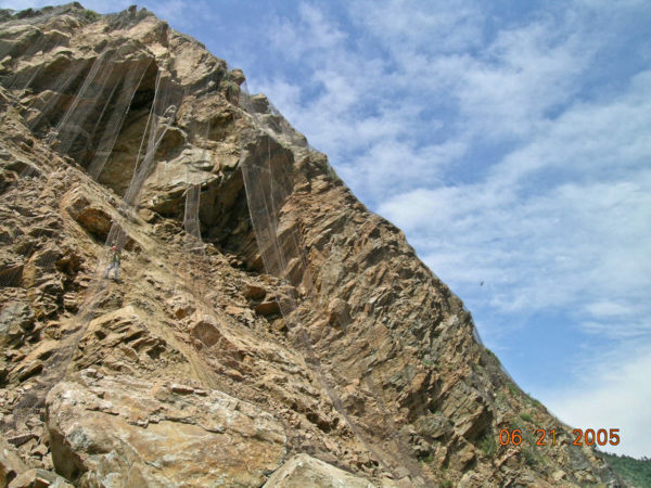 View of the slip surface looking north (i.e., the surface of a pegmatite intrusion). The installation of wire mesh to control the inevitable small rocks falling. Photo credit: Vince Matthews for the CGS.