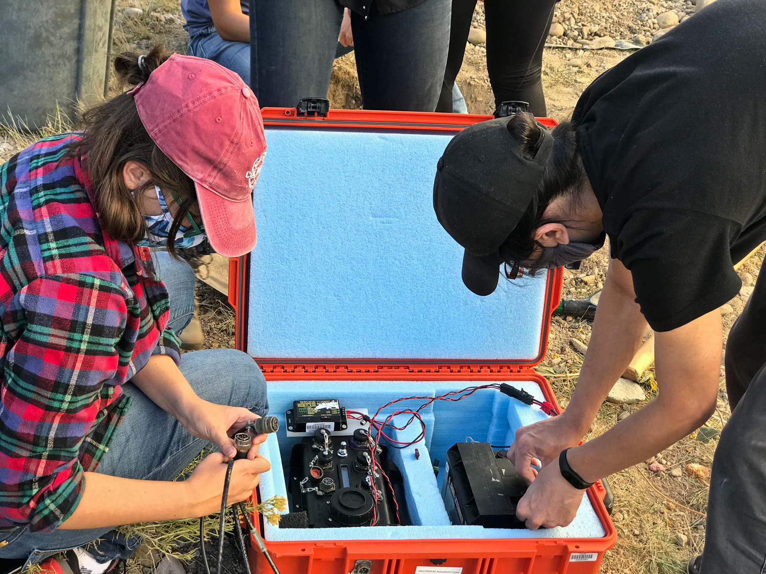 Postdoc Neala Creasy and visiting student Ridvan Orsuvan connect the solar-panel/battery-powered Reftek RT130 digitizer to the seismometer feed cable. Photo credit: Ebru Bozdag.