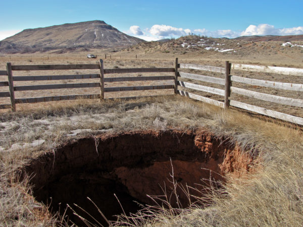 One of many sinkholes in the Larimer County Red Mountain Open Space where the Lykins Formation contains thick beds of gypsum. Table Mountain is in background at left. View is to the southwest. Photo credit: Jon White for the CGS.